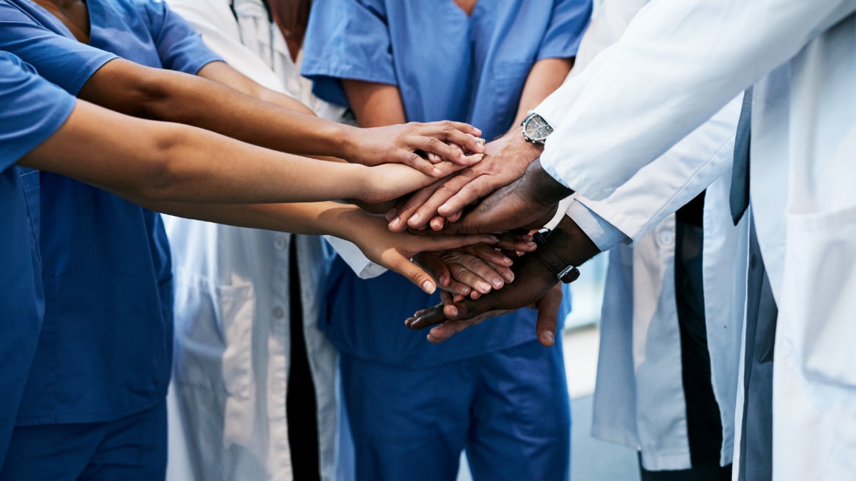 Healthcare workers all hands in a symbol of teamwork