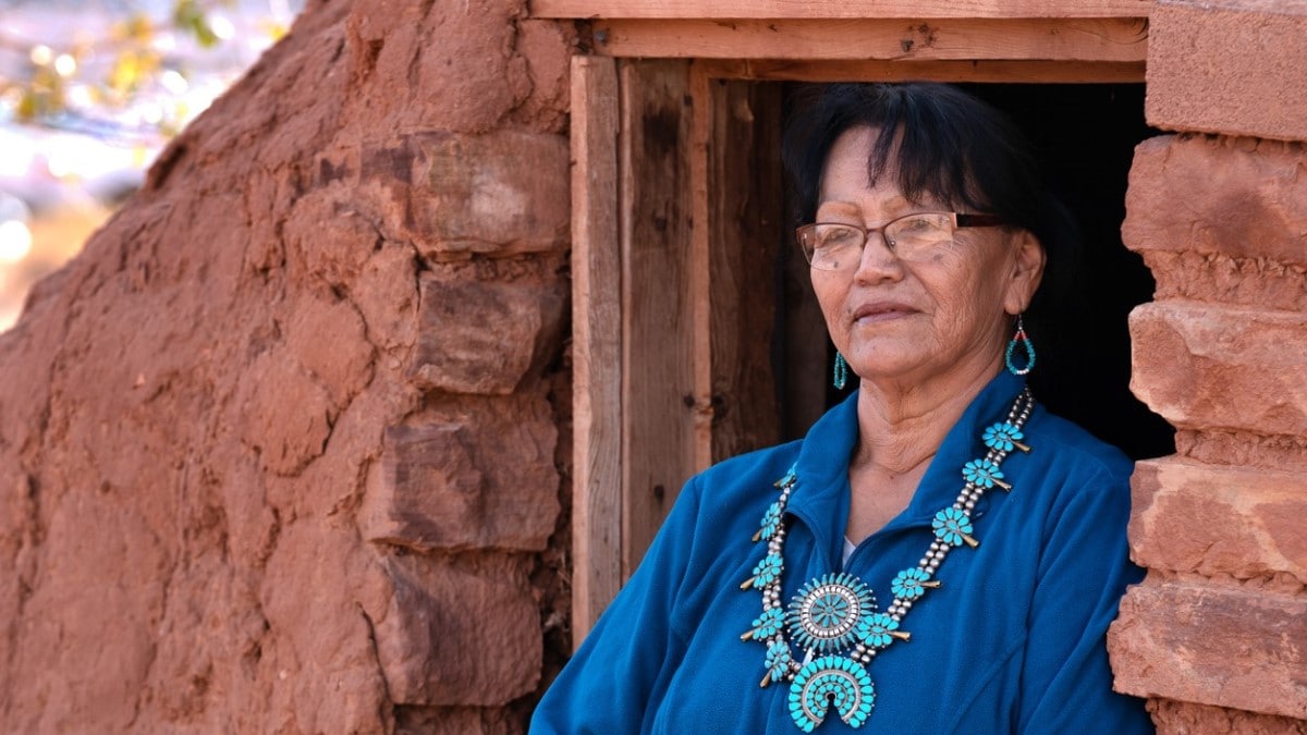 Senior Navajo woman standing outside a traditional hogan in Monument Valley, Arizona