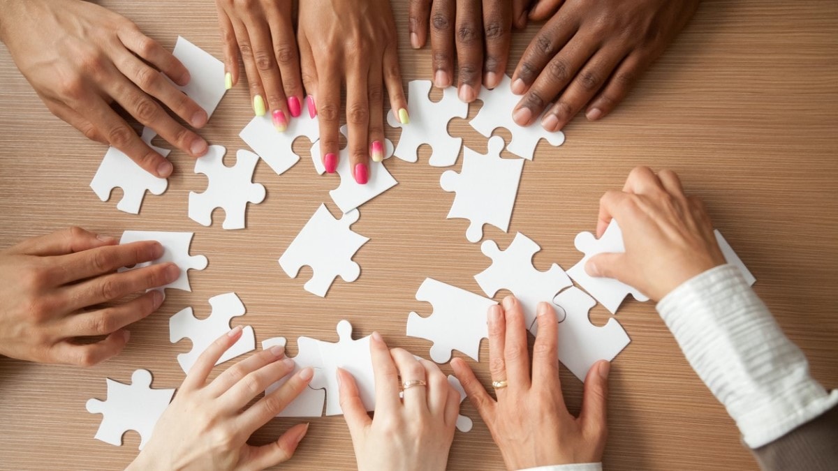 Hands of multi-ethnic business team assembling jigsaw puzzle