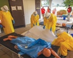 Thumbnail of Constructed mock Ebola Treatment Unit used during the Centers for Disease Control and Prevention Ebola Safety Training Course, held at the US Federal Emergency Management Agency Center for Domestic Preparedness in Anniston, Alabama, USA, 2014–2015. Trainees prepare to place a simulated deceased patient into a body bag.