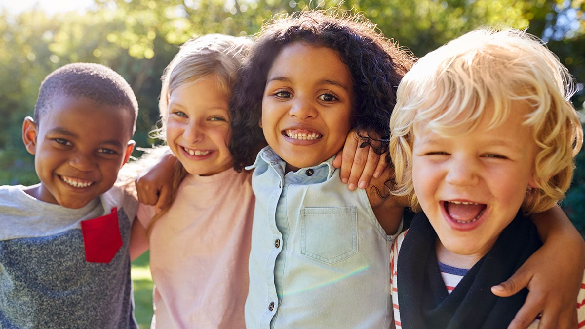 Diverse group of children smiling and embracing outside
