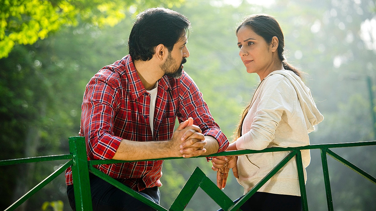 Young man and woman talking on a bridge at a park.