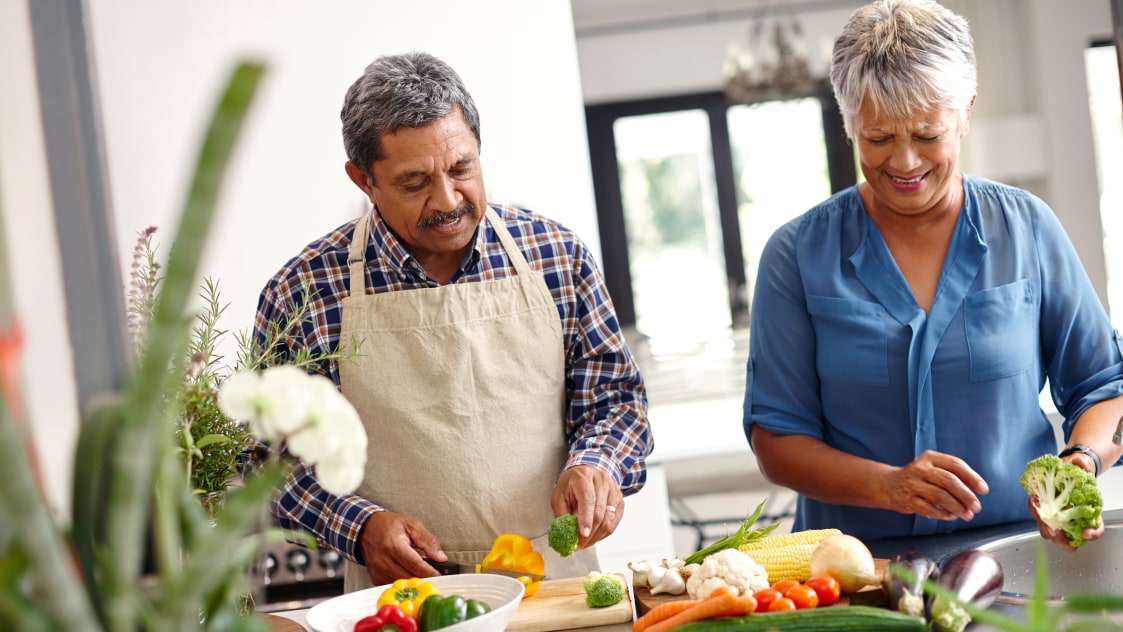 Middle-aged couple cutting vegetables