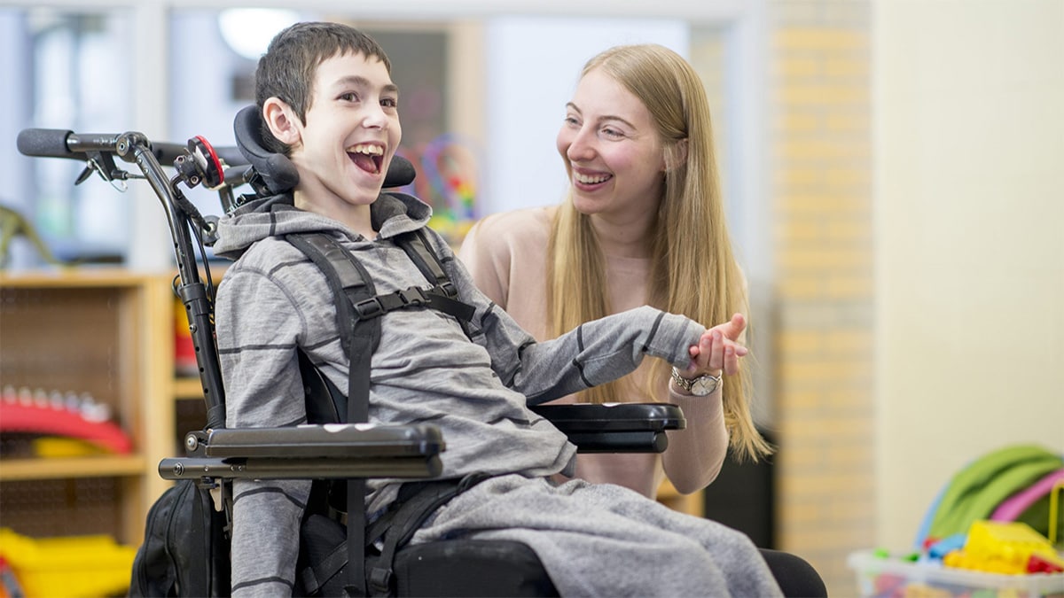 Caregiver sitting alongside student with a mobility disability.