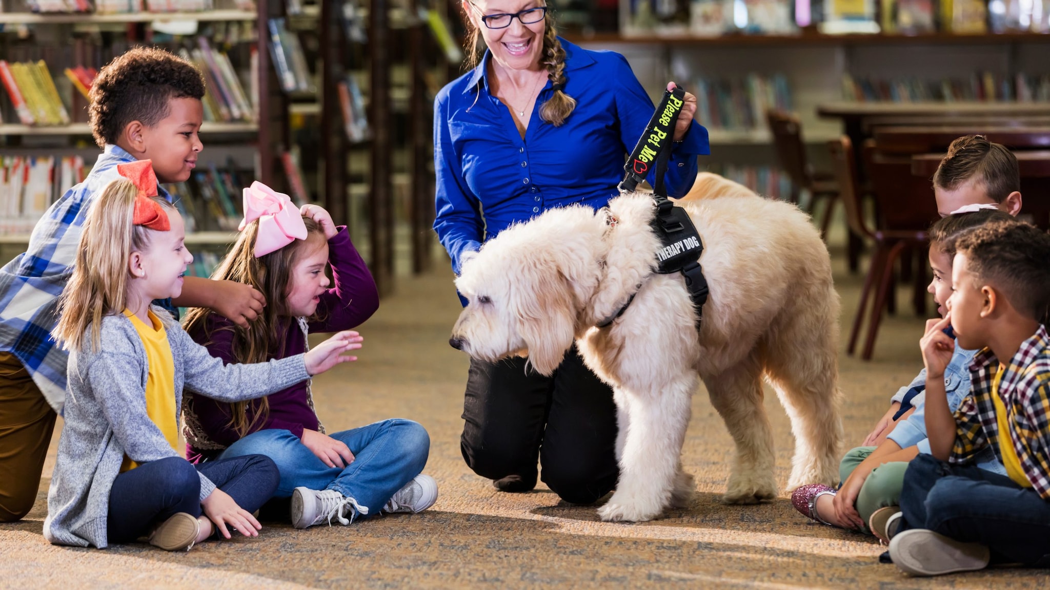 A therapy dog and its handler visit children in a school library