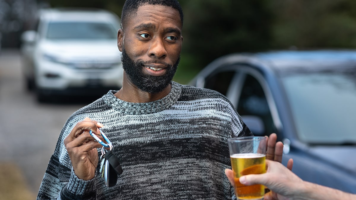 A guy refusing an alcohol drink while holding car keys.