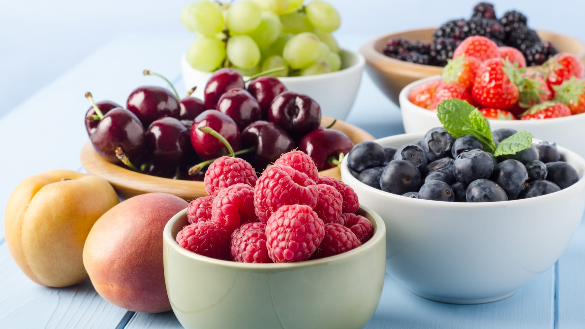 Small bowls with fruit including raspberries, cherries, and blueberries.