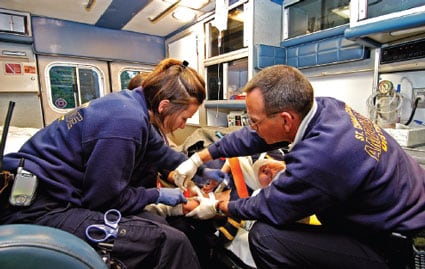 Perfil de dos param%26eacute;dicos en una ambulanza que atienden a un paciente en una camilla