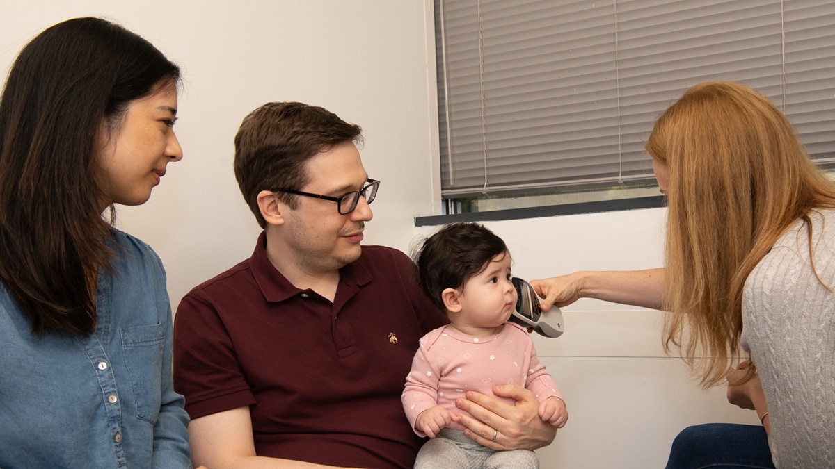A family takes their infant daughter to get a follow-up hearing test with an audiologist