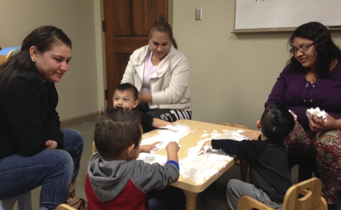 Legacy mothers talking with their children during creative play with shaving cream.