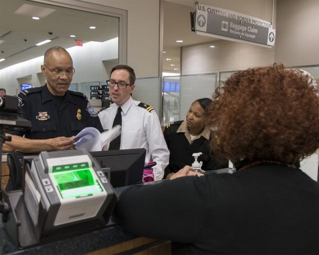 At the passport booth in an international airport, a Customs and Border Protection Officer works with two CDC Quarantine Public Health Officers to assess a sick traveler before allowing entry into the United States.