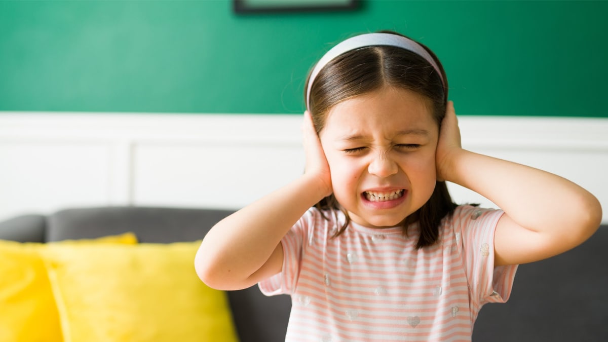 Young girl covering her ears because of loud sounds