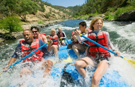 People white water rafting in a raft with paddles