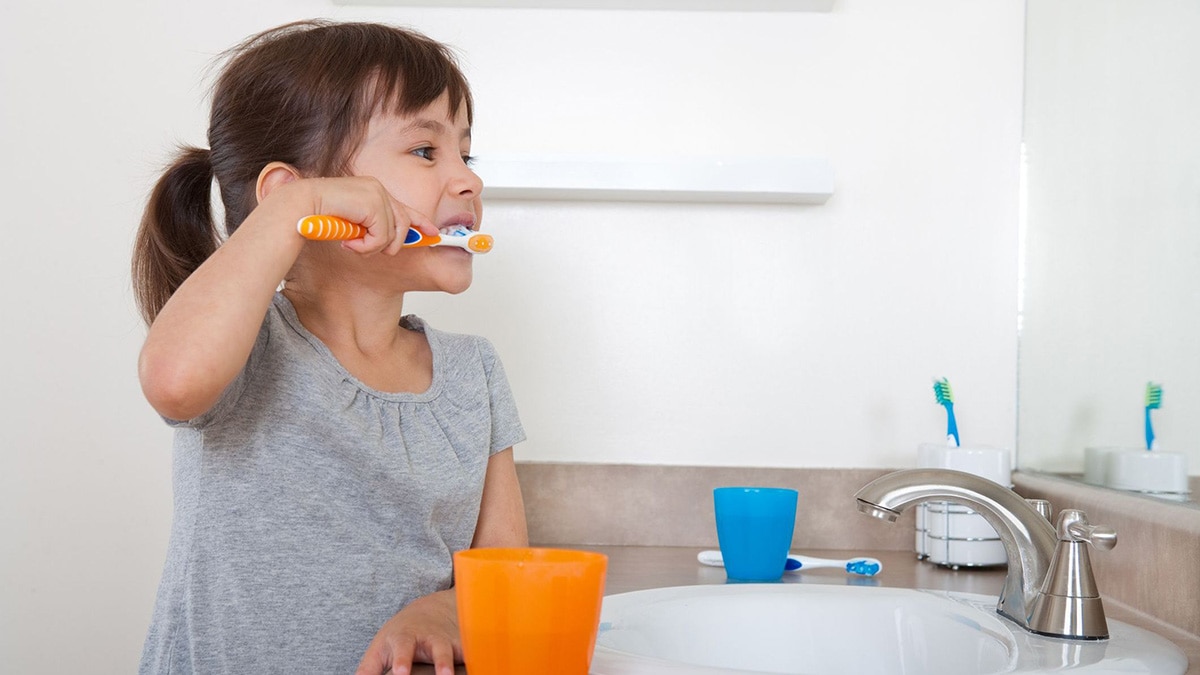 A girl brushes her teeth.