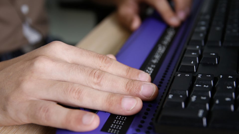 Close-up of white male hands typing on a computer keyboard.