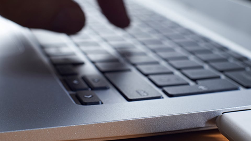 Close up image of hands typing on a laptop computer.