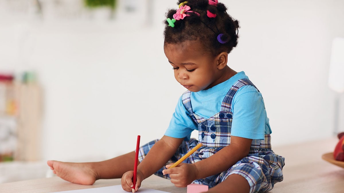 Cute toddler baby girl drawing with pencils using both hands