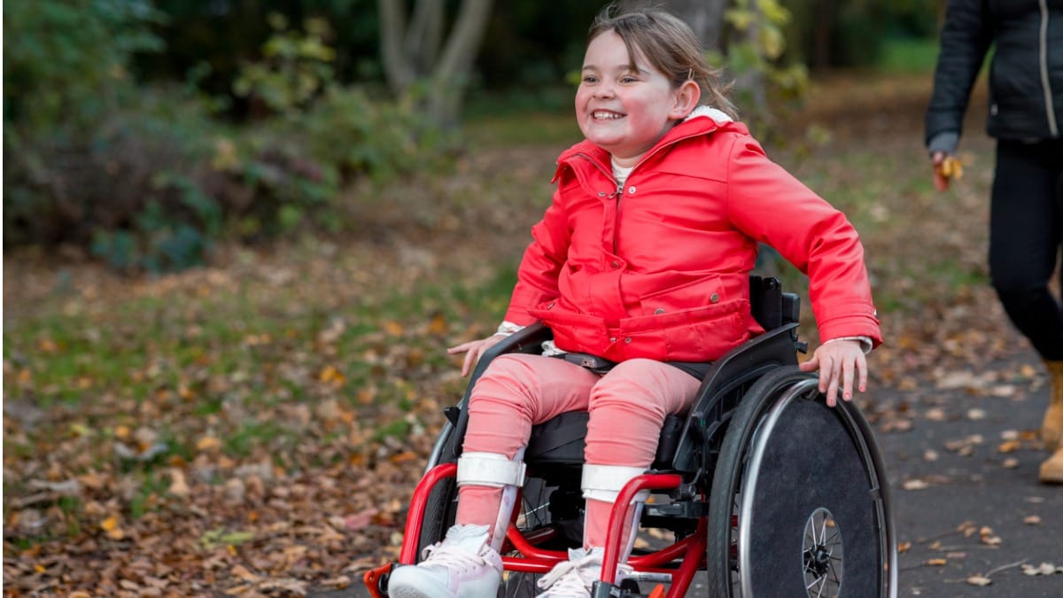 Girl in wheelchair rolling through park