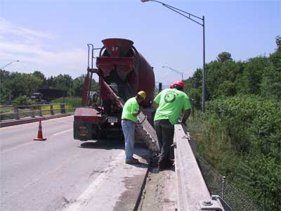 Photo 2. Paving company employees working at the rear end of the cement truck. (Photo was taken the day after work resumed, one month after the fatal incident. The cement truck and the workers pictured are in the same position as the victims at the time of the fatal incident.)