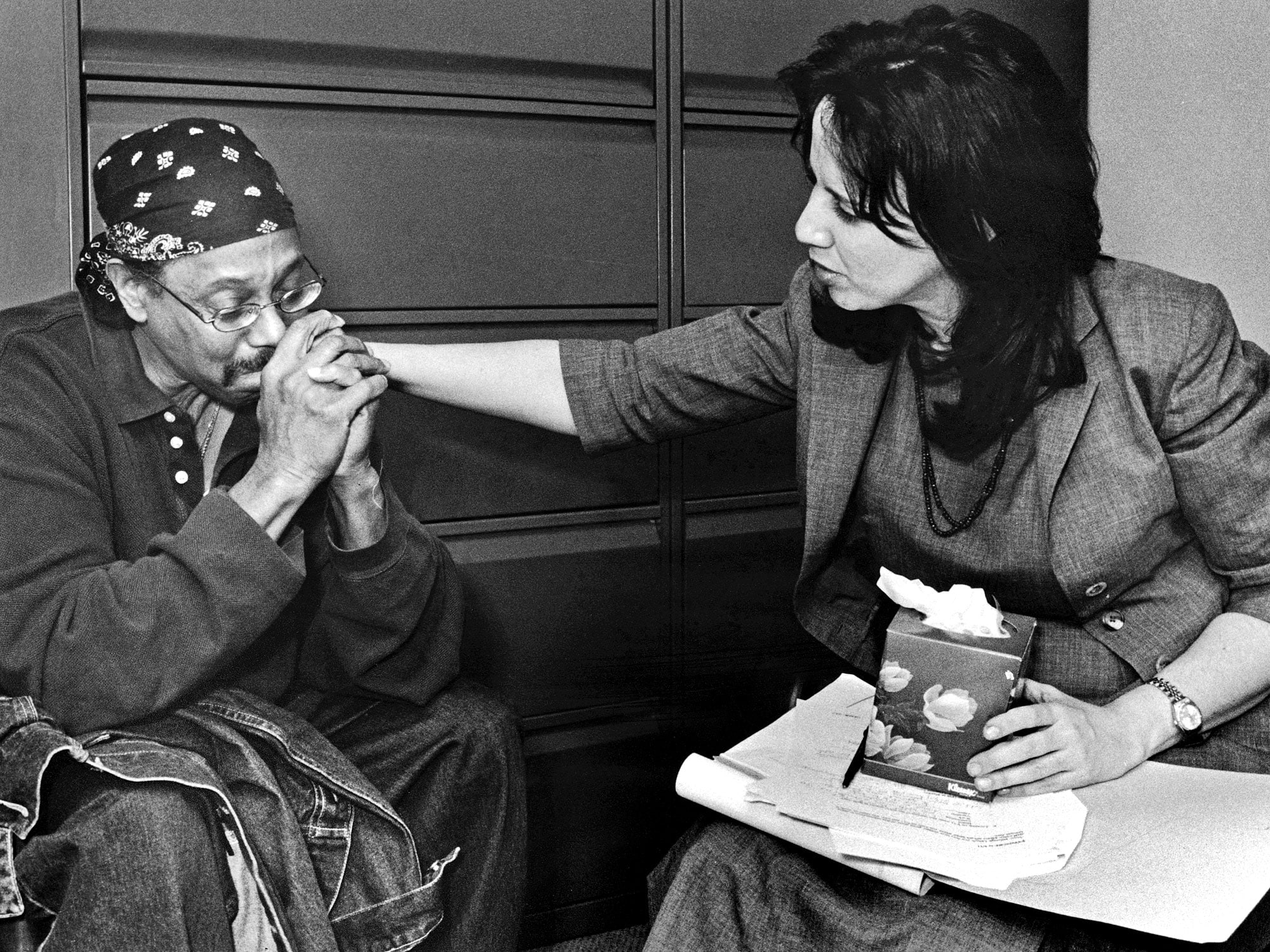 A woman placing a hand on a man's shoulder during a mental health screening.