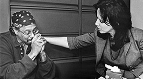 A woman placing an a hand on a man's shoulder during a mental health screening.