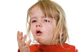 Una niña pequeña con un suéter rojo, tiene influenza y se ve enferma