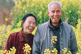 smiling older couple outside among flowers