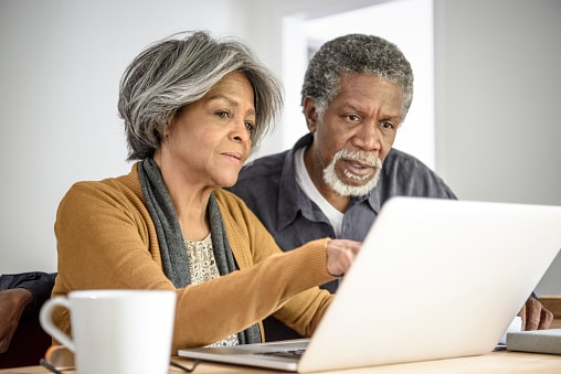 Senior couple on a laptop together with a serious expression.