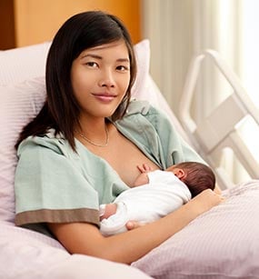 A breastfeeding mother in her hospital bed.