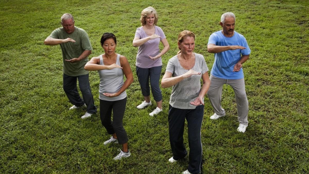 un grupo de hombres y mujeres que participan en una clase de tai chi
