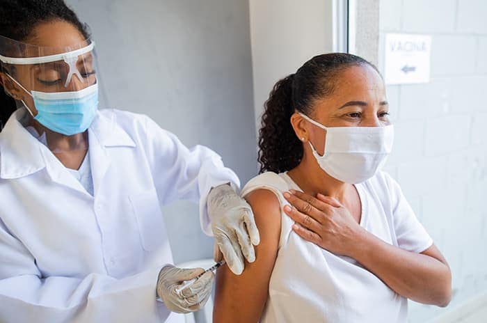 A healthcare professional providing a COVID-19 vaccine to her patient.