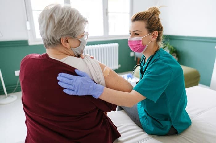 Foto de una enfermera que le da una vacuna contra la influenza a una mujer