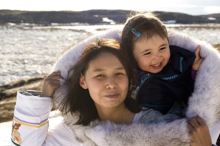 An Inuit mother has her daughter in her amouti, a traditional way to carry the young people.