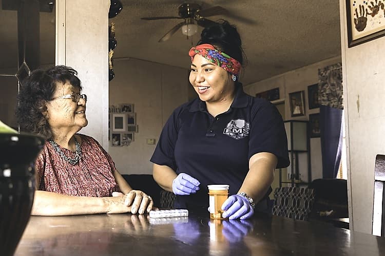 Una trabajadora de salud comunitario ayuda a una mujer navajo con sus medicamentos
