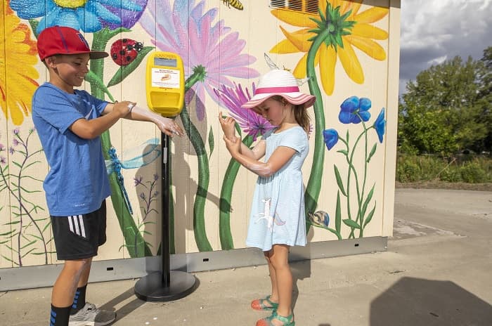 Kyle Davis y Hayley Davis se aplican protector solar de un dispensador en un parque de la ciudad de Reno.