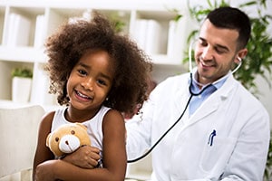 Smiling girl examined by doctor