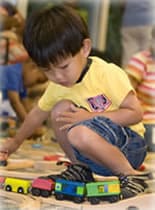 Photo of little boy playing with toy train.