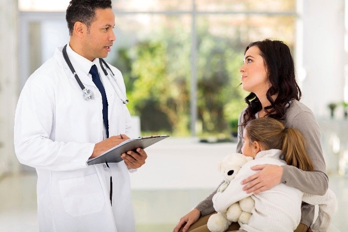 Mother holding her infant while talking to a doctor