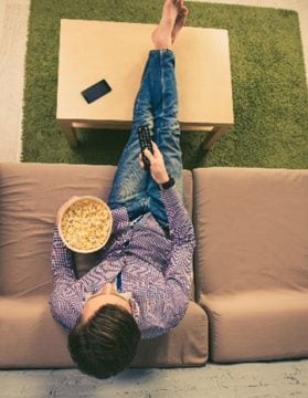 A person sitting on a couch eating popcorn