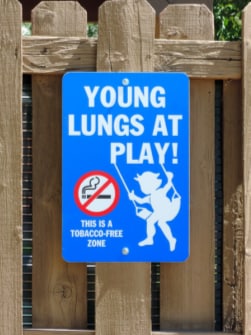 sign of do not smoke next to a child on a swing