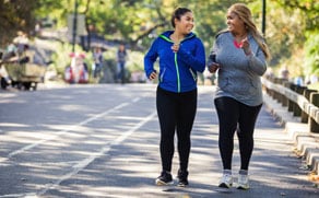 Two women running on sidewalk