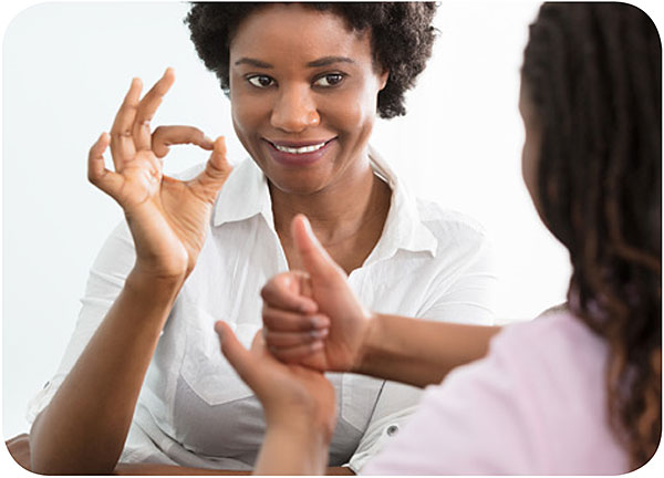 Mujer comunicándose con una niña en el language de señas.