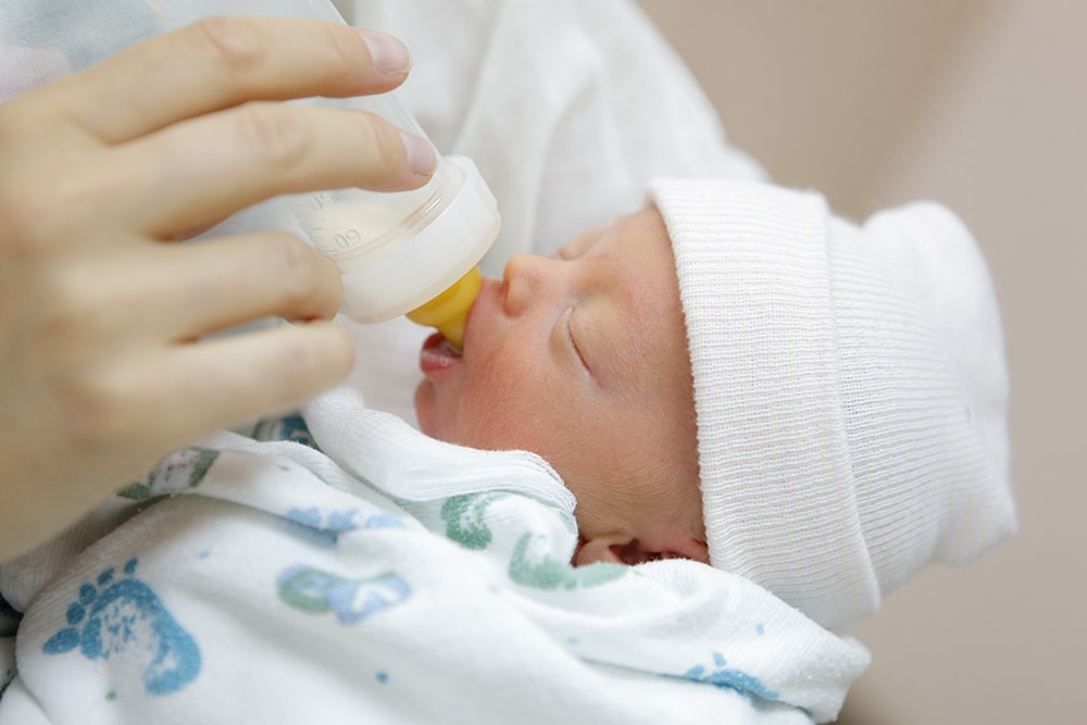 mother bottle feeding her premature baby in the hospital nursery