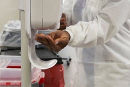 Healthcare worker in PPE using hand sanitizer