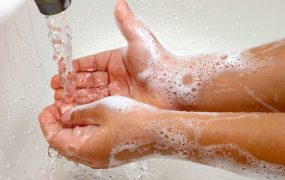 Una foto de una persona lavándose las manos con agua y jabón.