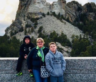A woman standing with her 2 sons in front of Mount Rushmore.