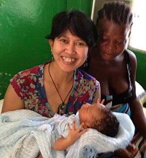 Endang holding a baby who, thanks to her team’s work, survived a complicated delivery, Haiti 2013