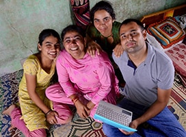 Indian family smiling as they look up from laptop
