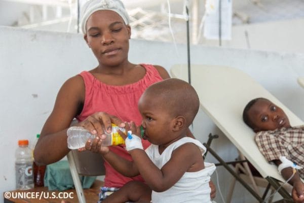 Woman holding bottle of water for child to drink