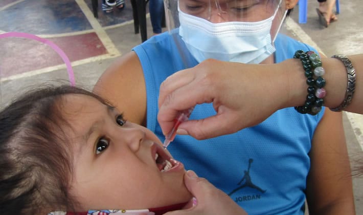 Young girl gets her oral polio vaccine in the Philippines.